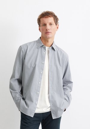 Striped button-up shirt in blue and white, cotton material, long sleeves, relaxed fit, textured fabric, paired with a white undershirt.