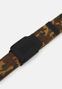 Ceinture en tissu à motif camouflage dans des tons terre avec une boucle en plastique noir portant l'inscription "URBAN CLASSICS" gravée. Tissage texturé, longueur ajustable.