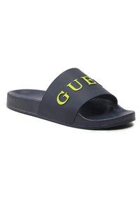 Navy blauwe schuifsandalen met een brede band en het verhoogde gele "GUESS" logo. Gladde textuur met een platte zool voor comfort.