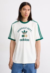 White short-sleeve t-shirt with green accents, featuring a central graphic "ORIGINALS DEPT. 1972 adidas" and three stripes on each shoulder.