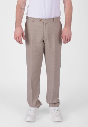 Pantaloni in lino marrone chiaro con taglio dritto, caratterizzati da una chiusura con bottone frontale e passanti per cintura, indossati con sneakers bianche.