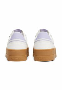 Sneakers bianche con una suola in gomma testurizzata, caratterizzate da dettagli in lavanda e una superficie liscia. Logo "TOMMY JEANS" sul tallone.