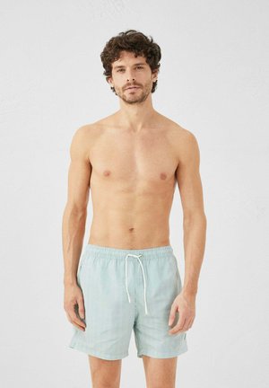 Bañador a rayas azul claro con cinturilla elástica y cordón. Cuenta con bolsillos laterales y un ajuste relajado.