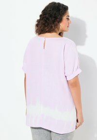 Blusa leggermente viola, con texture, maniche corte arrotolate, apertura a chiave sul retro e un motivo a gradiente bianco all'orlo. Vestibilità casual.