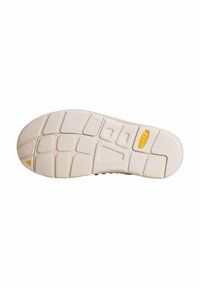 La semelle de la chaussure présente un design en caoutchouc texturé de couleur blanc cassé avec un support de voûte plantaire ajusté et un triangle accent jaune au talon.
