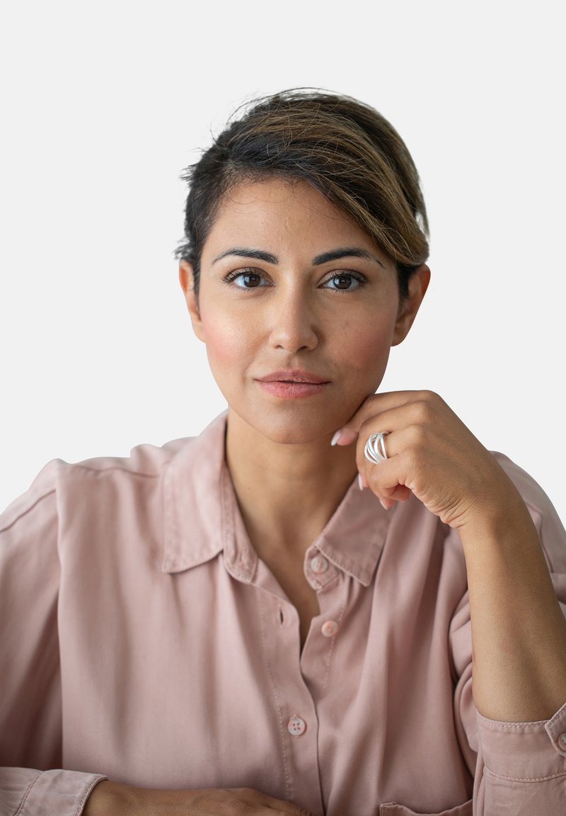 Camicia button-up rosa chiaro con colletto, carnagione skin-tone e un anello d'argento indossato sulla mano destra. Capelli corti, scuri con riflessi sottili.