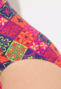 Monivärinen uimapuku, joka sisältää tilkkutyödesignin, jossa on kukkakuvioita ja geometrisia kuvioita eloisissa vaaleanpunaisen, violetin, Oranssin ja vihreän sävyissä.