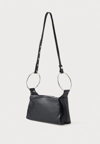 Bolso de mano de cuero negro con forma rectangular, que presenta anillos circulares plateados como asas y una textura suave. Correa ajustable con broches.