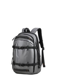 Zaino grigio con molteplici cinghie regolabili, fibbie di compressione e una finitura testurizzata. Presenta accenti neri e un logo sul lato.