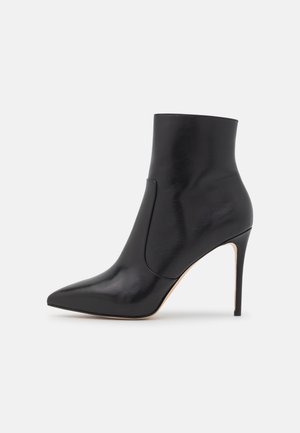 Stivale alla caviglia in pelle nera con punta affusolata, finitura liscia, panello elastico laterale e tacco a stiletto alto. Design minimalista.