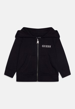 Czarna hoodie na zamek z bawełny, z przednią kieszenią, kapturem oraz białym logo "GUESS" na klatce piersiowej. Posiada ściągacze przy mankietach i u dołu.