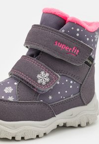 Grå vinterstövel med rosa accentkant och fleecefoder. Har kardborreband, snöflinge-mönster och en strukturerad gummisul.