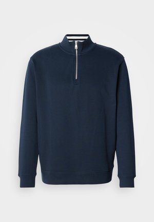 Granatowa bluza z wysokim kołnierzem i półzamkiem. Wykonana z miękkiego materiału, z prążkowanymi mankietami i dołem dla dopasowania.