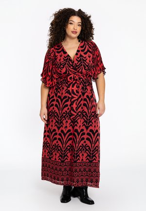 Rotes und schwarzes langes Wickelkleid mit floralem Muster, kurzen flatternden Ärmeln und einem Bindegürtel in der Taille, kombiniert mit schwarzen Knöchelstiefeln.