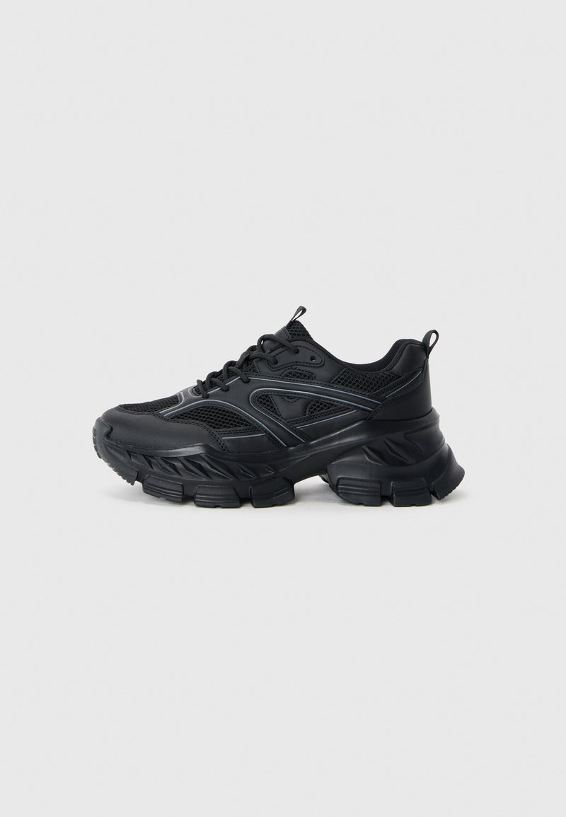 Black athletic shoes with a mesh upper and synthetic overlays, featuring a thick, textured sole with a distinctive tread pattern.