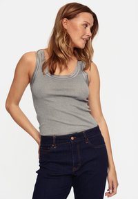 Top de tirantes acanalado gris con tirantes anchos y escote redondeado, combinado con jeans azul oscuro que tienen detalles de costura naranja.