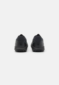Black athletic shoes with a textured outsole and cushioned heel. Features a smooth upper with minimal design and subtle reflective accents.