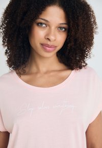 Šviesiai rožinė, trumpomis rankovėmis marškinėliai, pagaminti iš minkštos medžiagos, su balta kilniakraščio tekstu "Miegas išsprendžia viską". Apvalus iškirpimas.