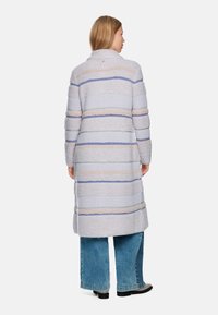 Long, cozy coat in light gray with horizontal stripes in cream and soft blue. Features a high collar and textured fabric. Pairing wide jeans.