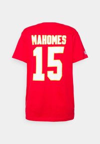 Raudona marškinė su geltonu ir baltu užrašu „MAHOMES“ ir numeriu „15“ nugaros pusėje. Trumpomis rankovėmis ir apvaliu iškirpimu.