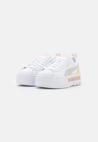 White platform sneakers featuring a textured sole, suede gray accents, and pastel yellow and pink details on the sides.
