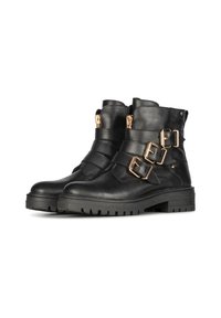 Bottines en cuir noir avec des boucles dorées, une semelle robuste et des coutures minimalistes. Le design comprend trois larges sangles sur le devant.