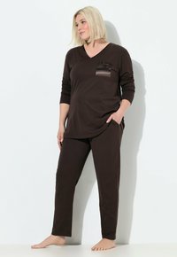 Camicia marrone a maniche lunghe con scollatura a V e tasca in satin, abbinata a pantaloni tapered coordinati. Realizzata in tessuto morbido e leggero.