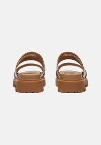 Brun sandal med två breda remmar och en vadderad sula, med en texturerad fotbädd och en hållbar, tjock gummiyttersula.