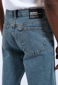 Jeans in denim azzurro chiaro con vestibilità rilassata, dotati di un'etichetta nera DRDENIM sulla vita posteriore e due tasche posteriori con cuciture in vista.