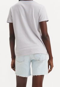 Grå randig t-shirt med korta ärmar och rund hals, tillsammans med ljusblå denimshorts med fransade kanter och bakfickor.