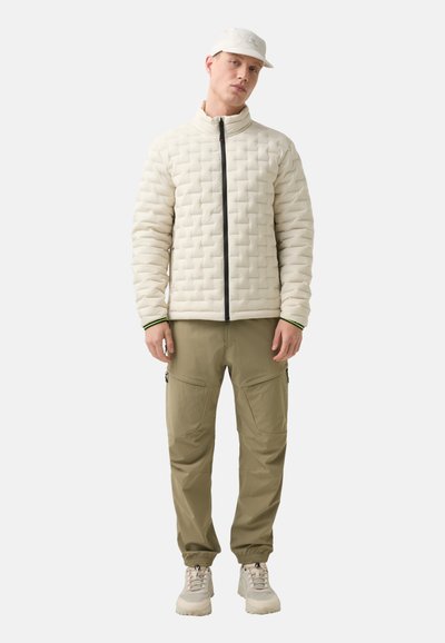A white, quilted jacket with a high collar and black zipper, paired with olive cargo pants featuring side pockets and adjustable cuffs.