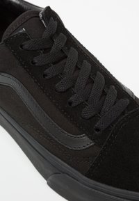 Baskets noires avec un mélange de suède lisse et de textile durable sur la tige, des lacets plats noirs et une semelle extérieure en caoutchouc texturée.