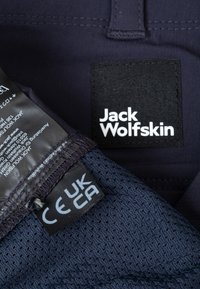 Marine stof met een gestructureerde, netvoering; bevat een label met de tekst "Jack Wolfskin" en certificeringsdetails.