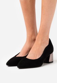 Scarpe chiuse in suede nero con punta affusolata e tacco blocco testurizzato in argento metallizzato. Finitura liscia e design minimalista.