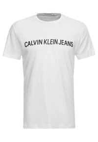 Bílý bavlněný tričko s nápisem "CALVIN KLEIN JEANS" v tučných černých písmenech přes hrudník; krátké rukávy a kulatý výstřih.