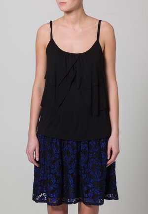 Haut sans manches noir avec un design à volants superposés ; associé à une jupe en dentelle bleue de longueur genou avec des motifs floraux et une doublure noire.