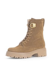 Brune suede ankelstøvel med tykk plattformsåle, snøring foran, og en gullfarget spenne detalj på siden.