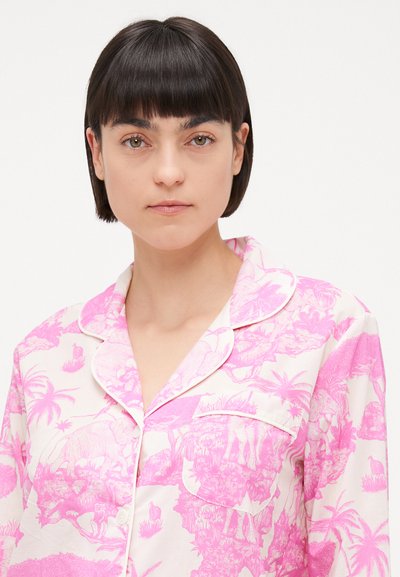 Short-sleeve pajama top in soft fabric, featuring a pink tropical animal print on a light background; detailed with contrasting white piping.