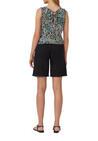 Pantaloni corti neri e un top senza maniche con un motivo geometrico colorato e un dettaglio a chiave sulla schiena. Il tessuto testurizzato aggiunge interesse visivo.