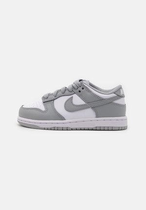 Nike Dunk Low tenisice u sivoj i bijeloj koži, s perforiranim prstom, podstavljenim okovratnikom i ravnom vezanjem. Potplat osigurava prianjanje.
