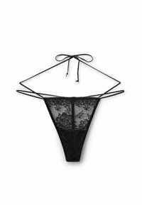 String en dentelle noire présentant des motifs floraux complexes, des liens ajustables sur les côtés et une texture transparente. Design à couverture minimale.