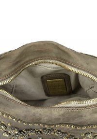 Interno della borsa in suede grigio con zip dorata, rivestimento testurizzato e borchie decorative in metallo. Etichetta visibile all'interno con dettagli del marchio e della produzione.