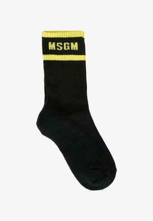 Calzini neri a costine con strisce gialle in cima e il logo "MSGM". Il design mette in evidenza uno schema di colori contrastanti.