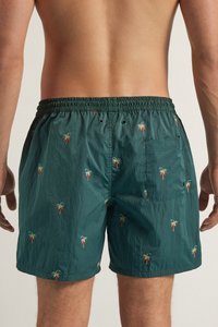 Bañadores para hombre en nylon verde oscuro con bordado de palmeras por todo el tejido. Cintura elástica con cuerda de ajuste; un bolsillo trasero.