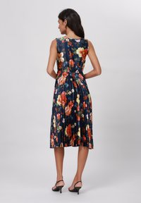 Rochie plisată florală cu un fundal bleumarin, având un amestec vibrant de culori. Design fără mâneci cu talie strânsă și fustă fluidă.