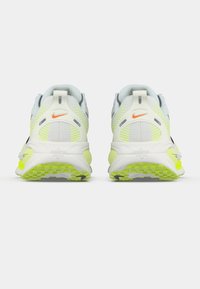 Sportske cipele s pretežno svijetlosivim gornjim dijelom, fluorescentno žutim naglascima i crnim detaljima. Imaju mrežasti dizajn i teksturiranu potplat.