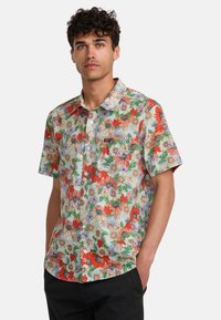Short-sleeve button-up shirt in a floral pattern with red and purple flowers on a light blue background; features a chest pocket and relaxed fit.