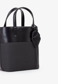 Borsa tote nera con parte superiore in pelle lucida e sezione inferiore in tessuto texturizzato. Presenta doppi manici e un'etichetta pendente con logo impresso.