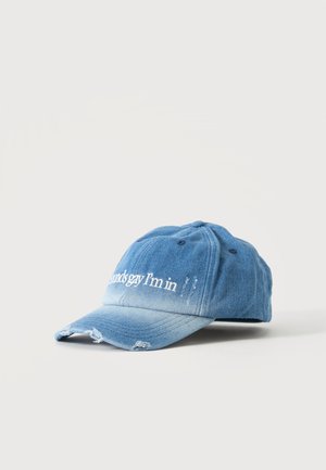 Casquette de baseball en jean bleu clair avec bords effilochés et texte brodé blanc partiel à l'avant.