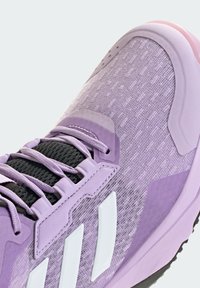 Purple athletic shoe featuring a textured mesh upper, black laces, and white accents. The sole has a pink color.
